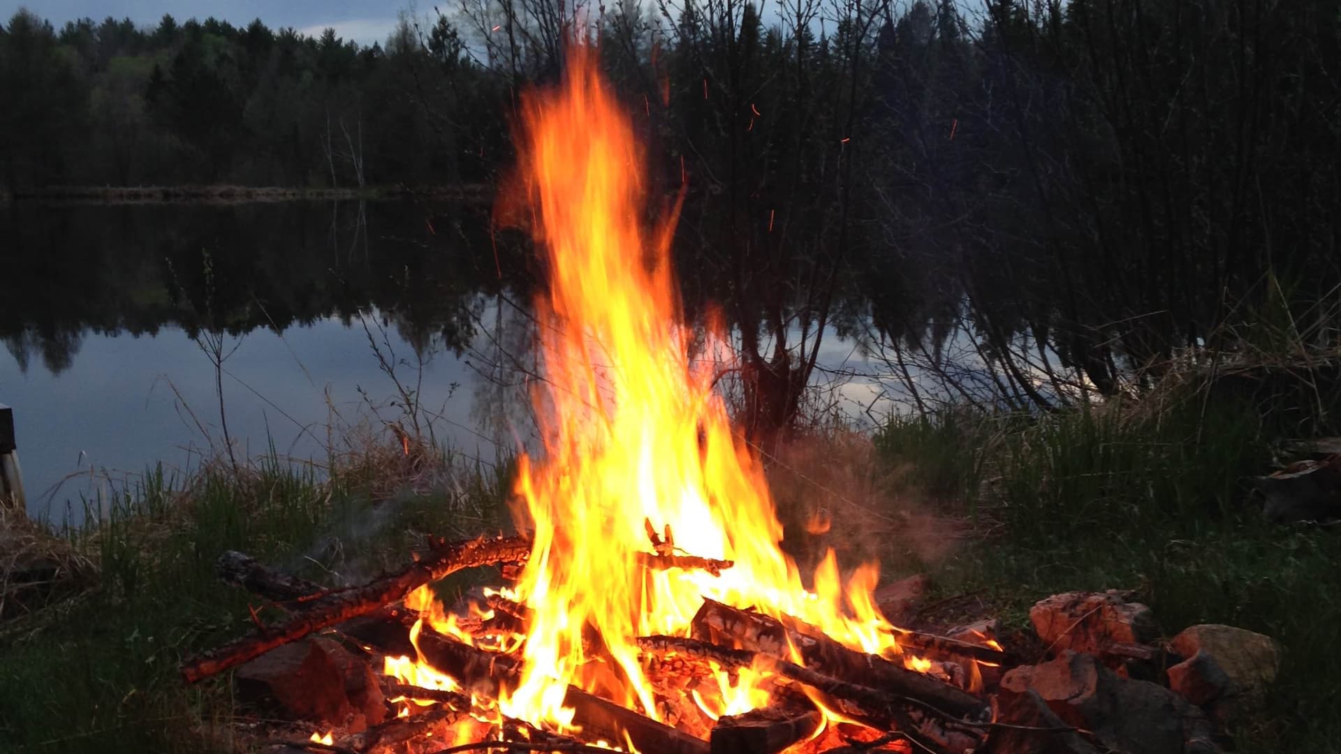 A campfire burns brightly in the evening